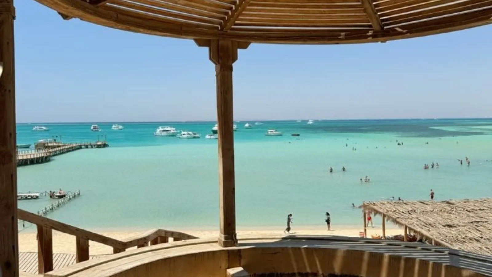 View from a wooden pavilion over the turquoise lagoon and boats at Orange Bay, Giftun Island