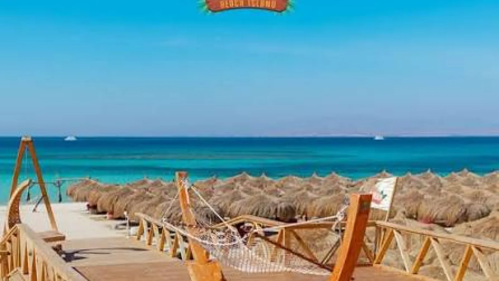 Hula Hula Beach Island sign above a wooden deck with hammock and thatched umbrellas, Hurghada