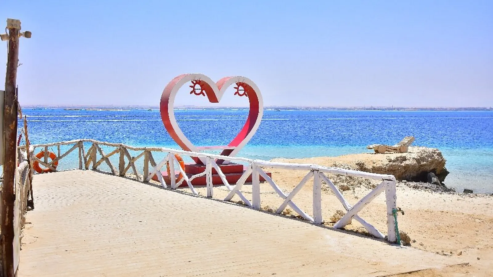 White and red heart sculpture on a wooden pier by the sea on Magawish Island, Hurghada