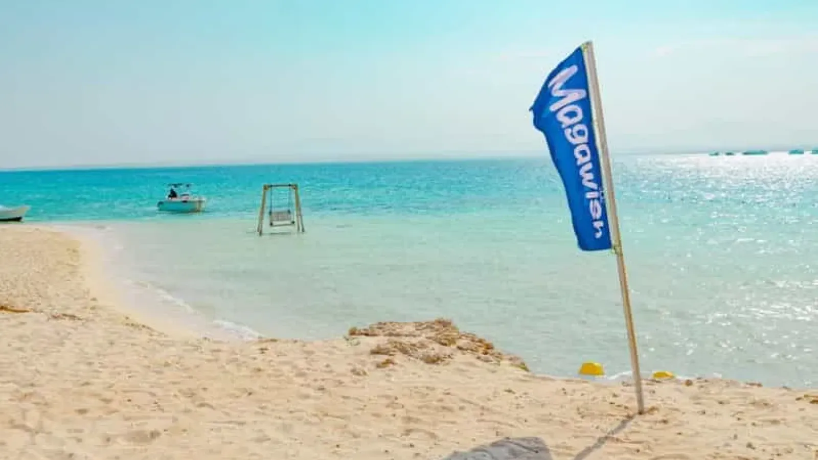Magawish flag on the beach with a swing standing in the shallow sea, Magawish Island