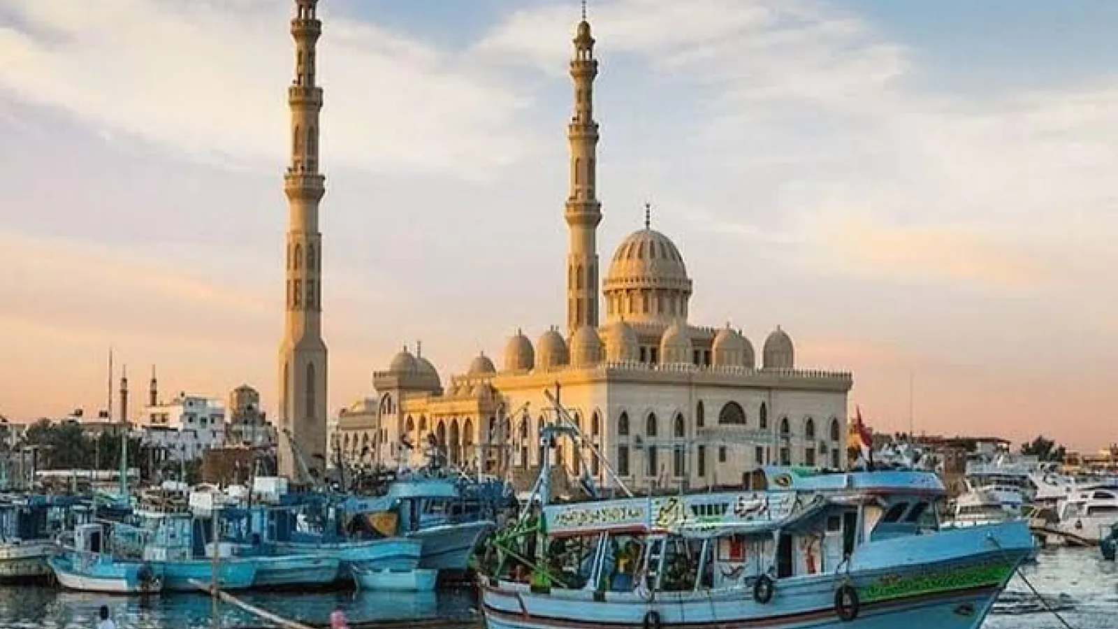 El Mina Mosque minarets rising over fishing boats in Hurghada harbour at sunset