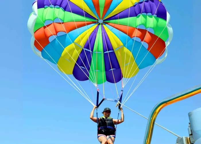 Parasailer with a rainbow parachute lifting off the boat platform in Hurghada