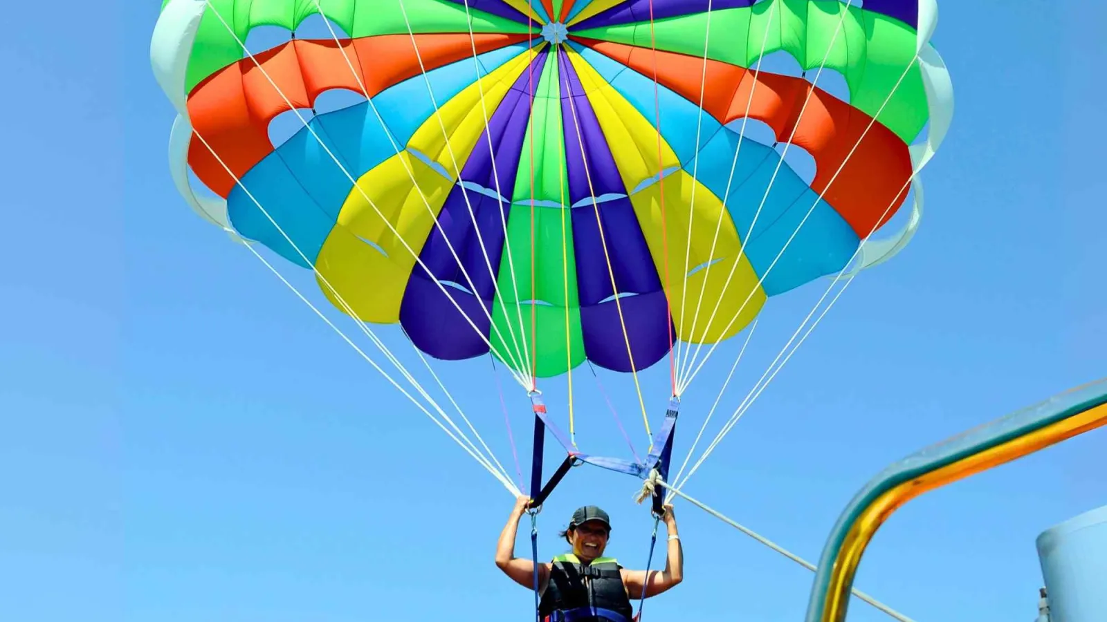 Parasailer with a rainbow parachute lifting off the boat platform in Hurghada