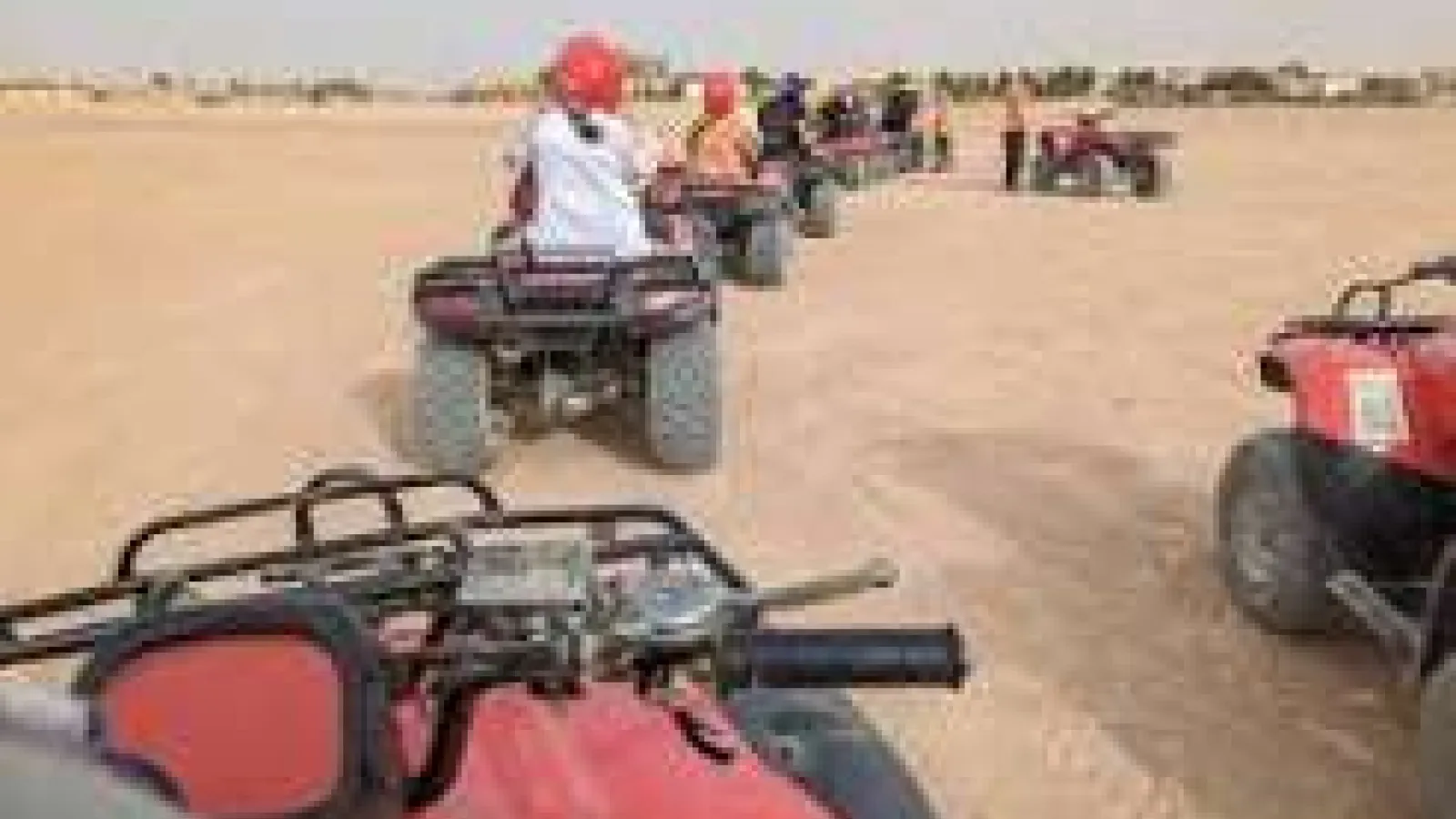 Group of riders on red quad bikes lined up in the desert near Hurghada