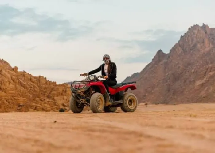 Rider in a headscarf on a red quad bike among the desert mountains near Hurghada