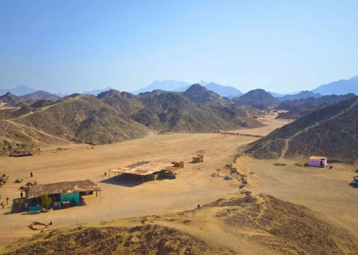 Bedouin village with palm-roof shelters in a desert valley near Hurghada