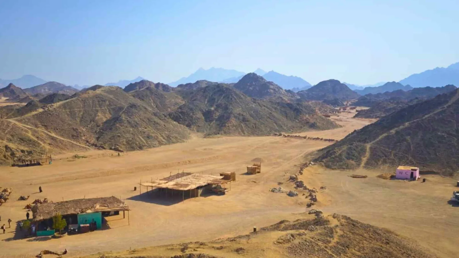 Bedouin village with palm-roof shelters in a desert valley near Hurghada