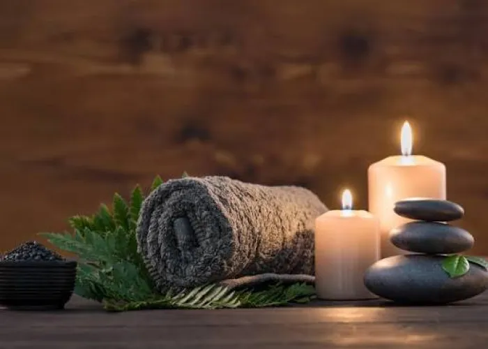 Rolled towel, candles and hot massage stones prepared for a spa treatment