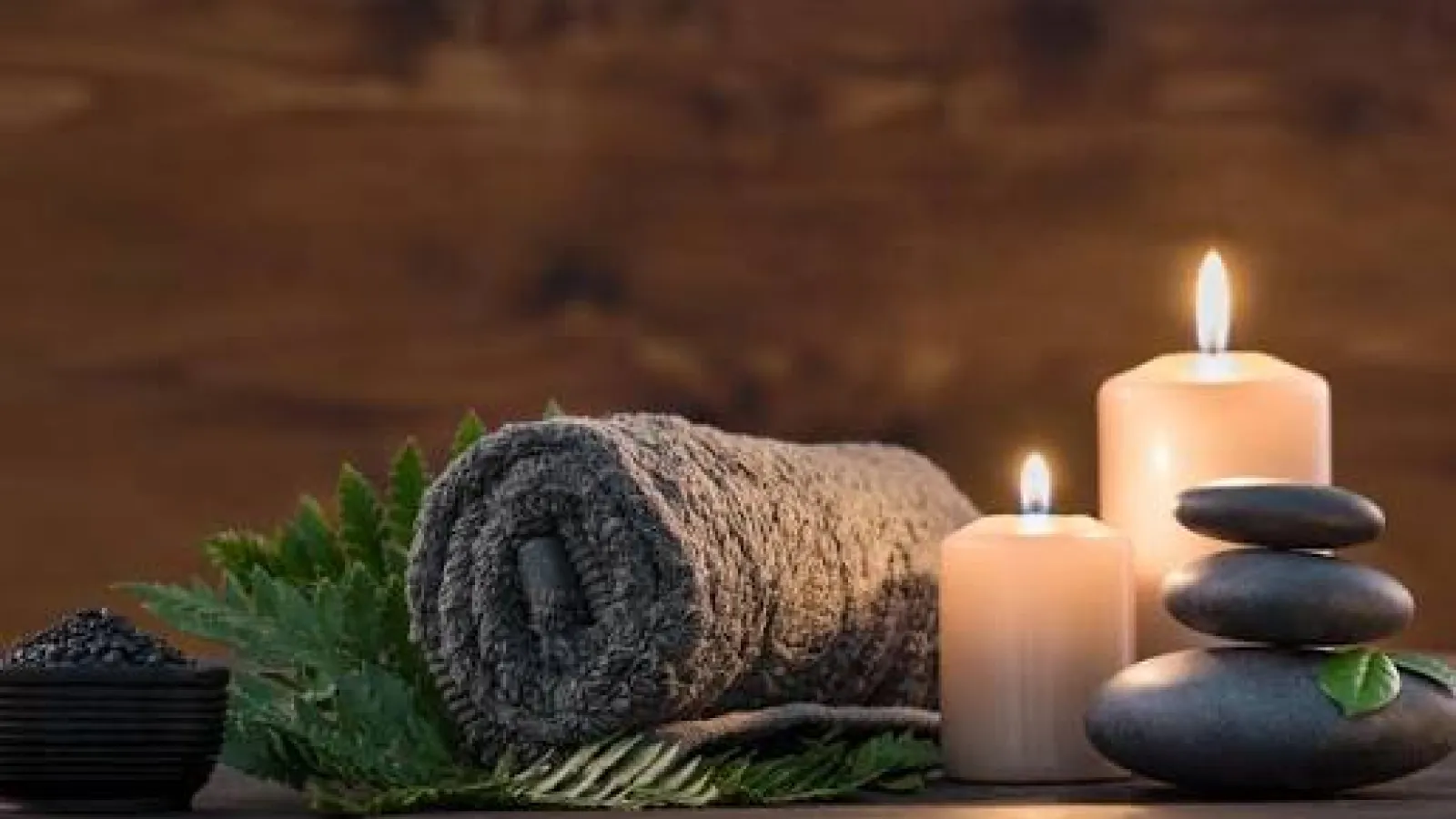 Rolled towel, candles and hot massage stones prepared for a spa treatment